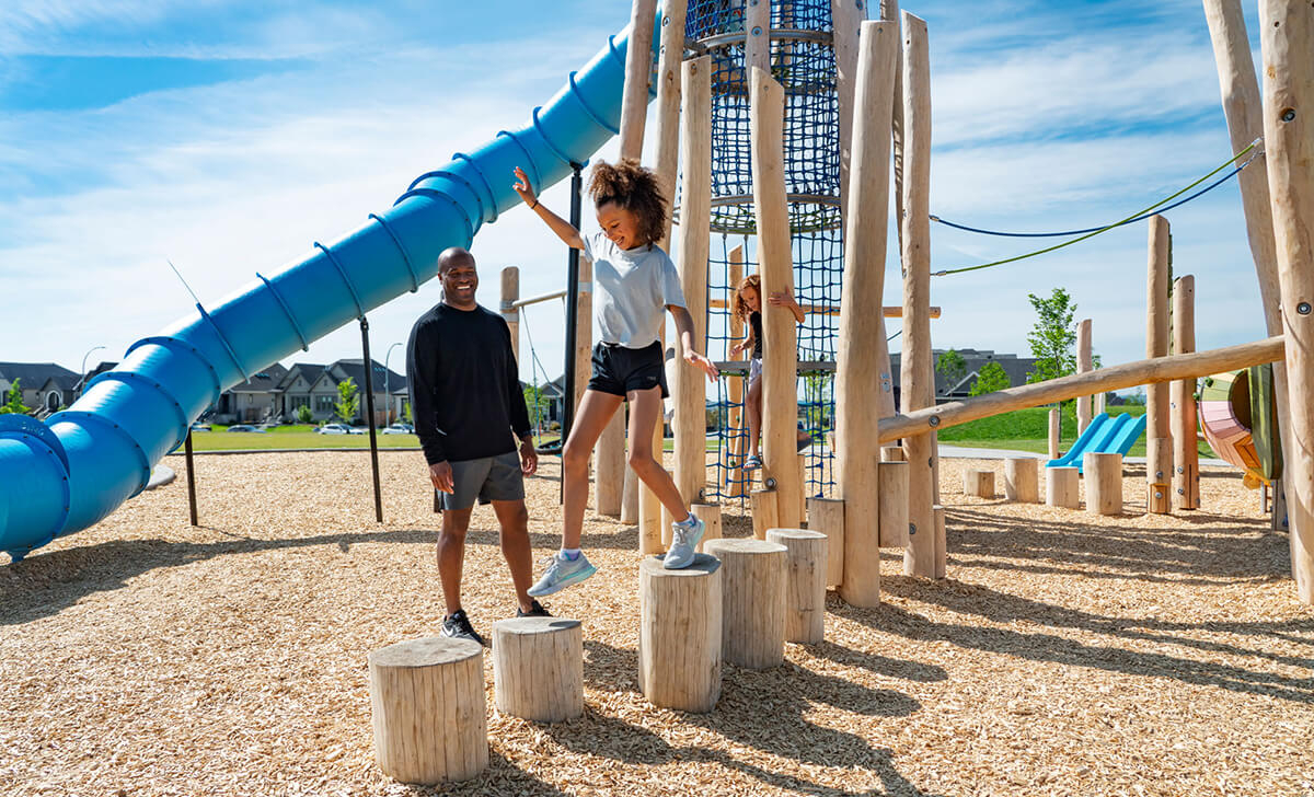Girls playing on playground as father watches