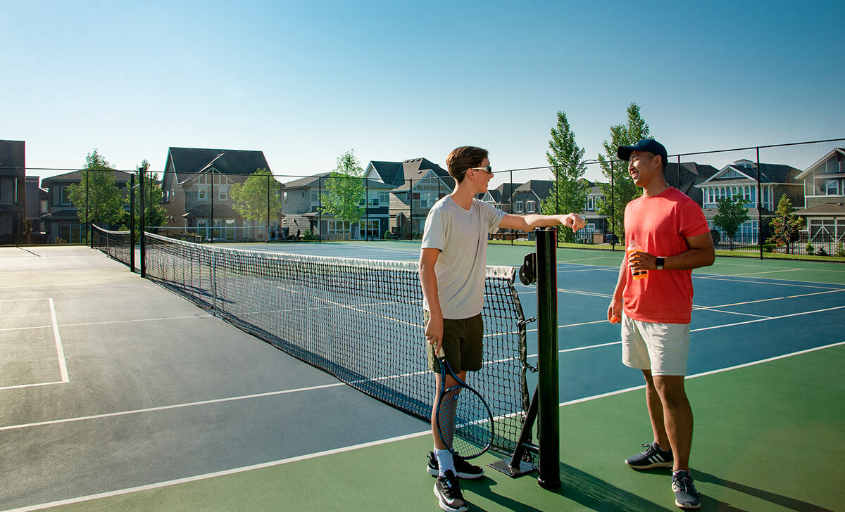 2 men standing at tennis net talking